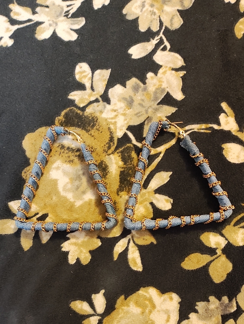 image features a pair of statement denim triangle hoop earrings wrapped in a gol